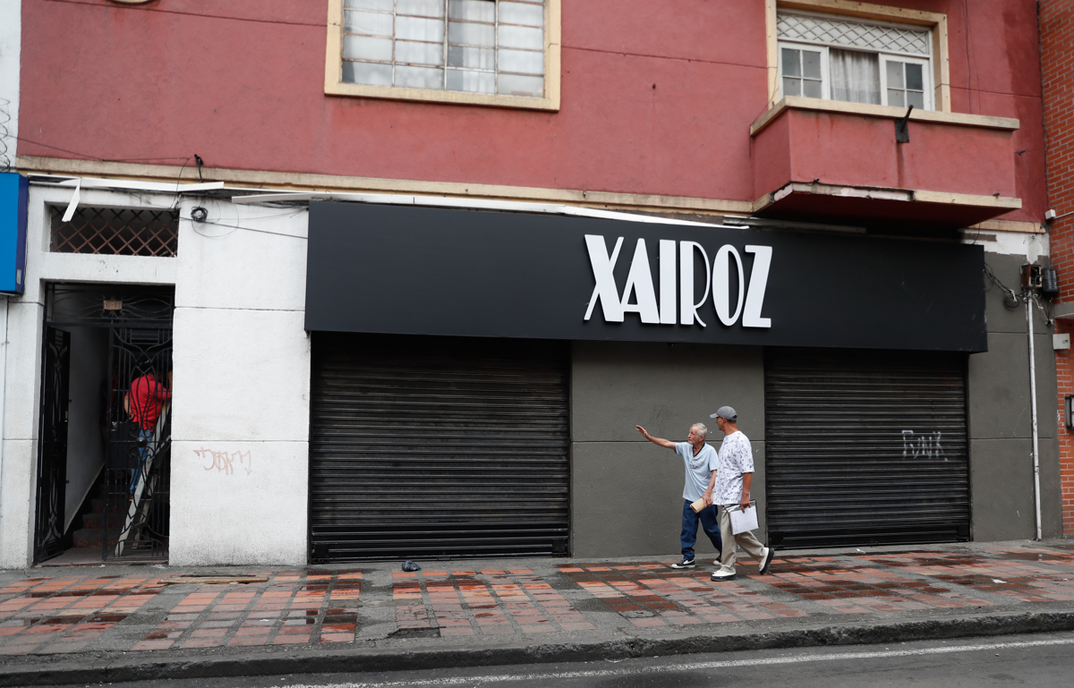Personas caminan frente a locales comerciales cerrados este miércoles, en el centro de Cali (Colombia). (Foto de Ernesto Guzmán de la agencia EFE)