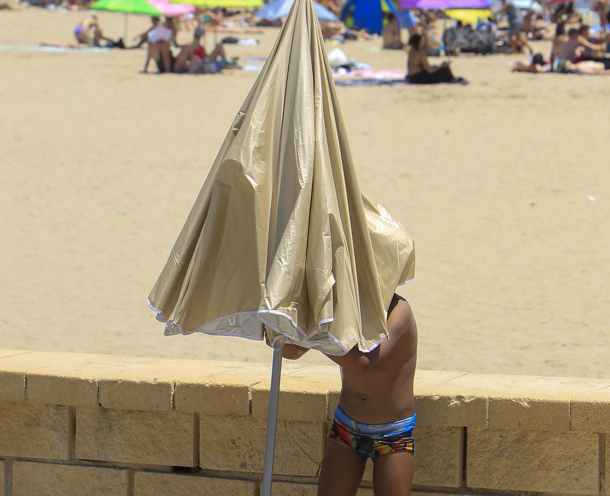 Una persona aguarda bajo una sombrilla en la playa de Alicante durante este jueves. (Foto de Morell de la agencia EFE)
