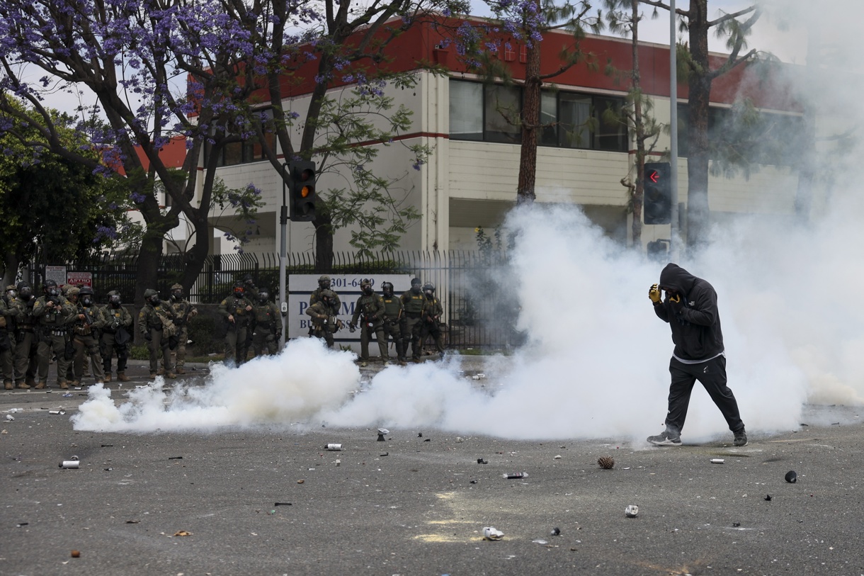 Un manifestante camina a través del humo de granadas de humo aturdidoras disparadas por agentes federales cerca de un Home Depot después de que el Servicio de Inmigración y Control de Aduanas (ICE) realizara una redada en Paramount, California, EUA. (Foto de Allison Dinner de la agencia EFE)