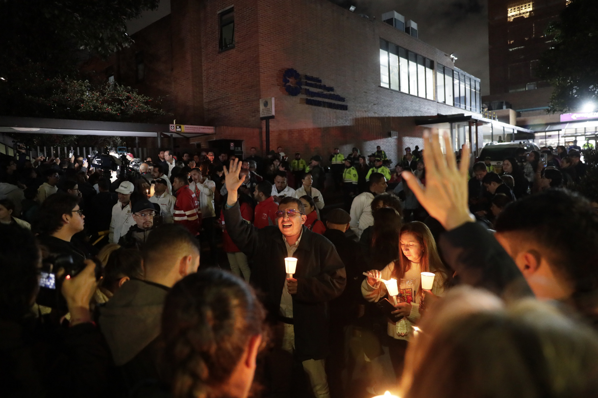 Personas encienden velas a las afueras de la Fundación Santa Fe donde fue trasladado el senador colombiano Miguel Uribe Turbay este sábado, en Bogotá (Colombia). (Foto de Carlos Ortega de la agencia EFE)
