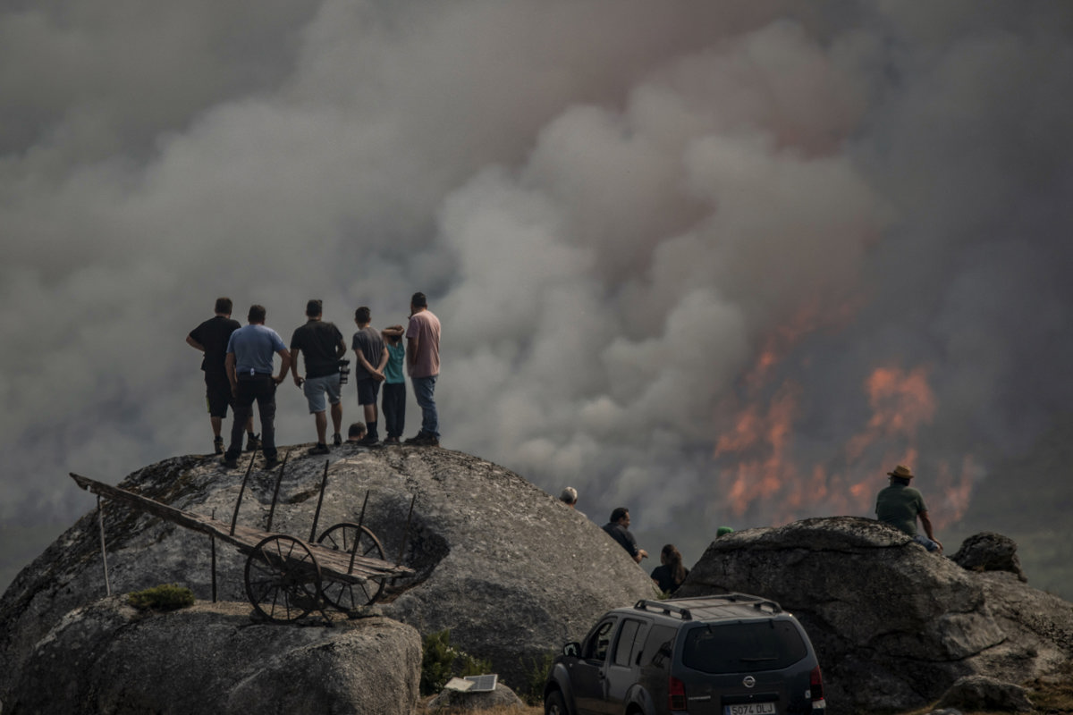 Varias personas observan el incendio forestal declarado ayer en Avión (Ourense), este lunes. (Foto de Brais Lorenzo de la agencia EFE)