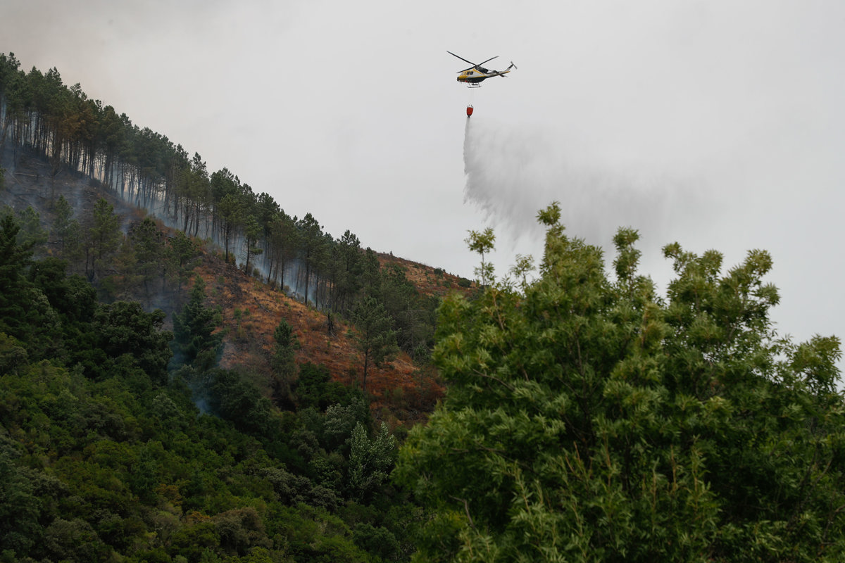 Un helicóptero realiza labores de enfriamiento del terreno, este miércoles en una zona montañosa de Augasmestas, en Quiroga (Lugo, Galicia). (Foto de Eliseo Trigo de la agencia EFE)