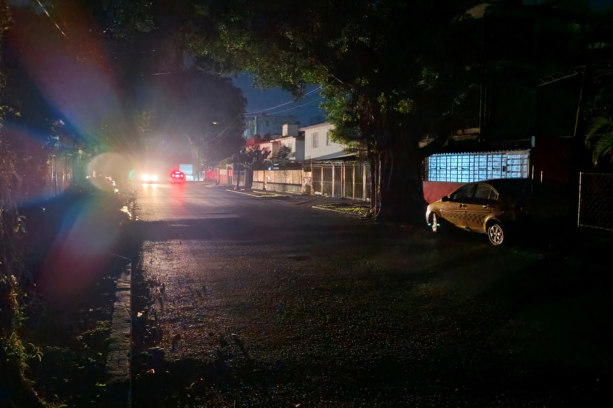 Una calle en penumbra e iluminada por las luces de 2 automotores, durante uno de los diarios cortes de energía eléctrica, en La Habana (Cuba). (Foto de archivo de Ernesto Mastrascusa de la agencia EFE)
