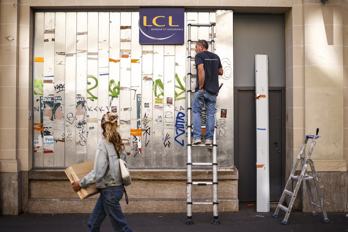 Un trabajador protege el frente de un banco. (Foto de Yoan Valat de la agencia EFE/EPA)