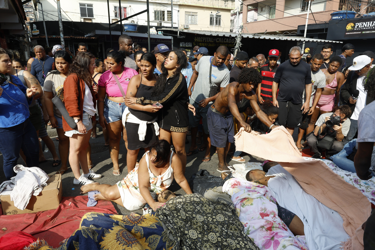 Personas observan cuerpos sin vida en una calle después de un operativo policial este miércoles, en Río de Janeiro (Brasil). (Foto de Antonio Lacerda de la agencia EFE)