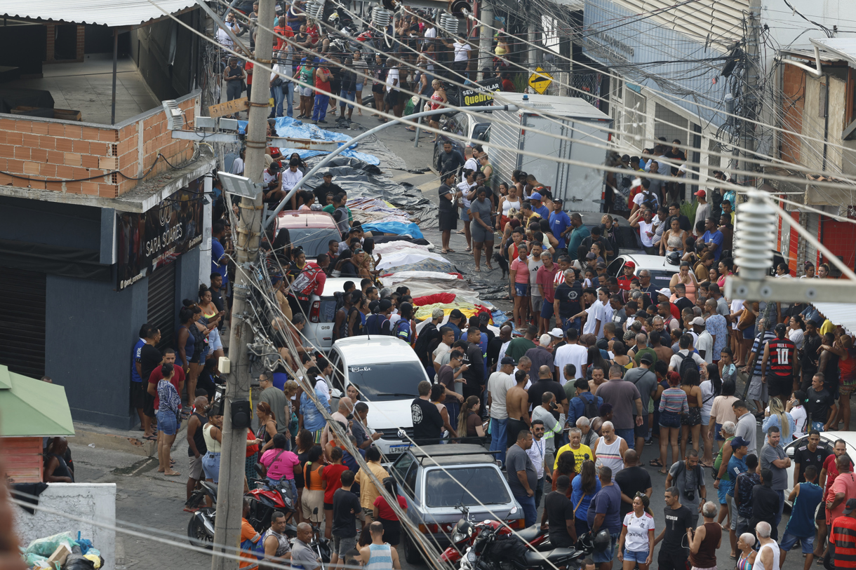 Personas observan cuerpos sin vida en una calle este miércoles, en Río de Janeiro (Brasil). (Foto de Antonio Lacerda de la agencia EFE)