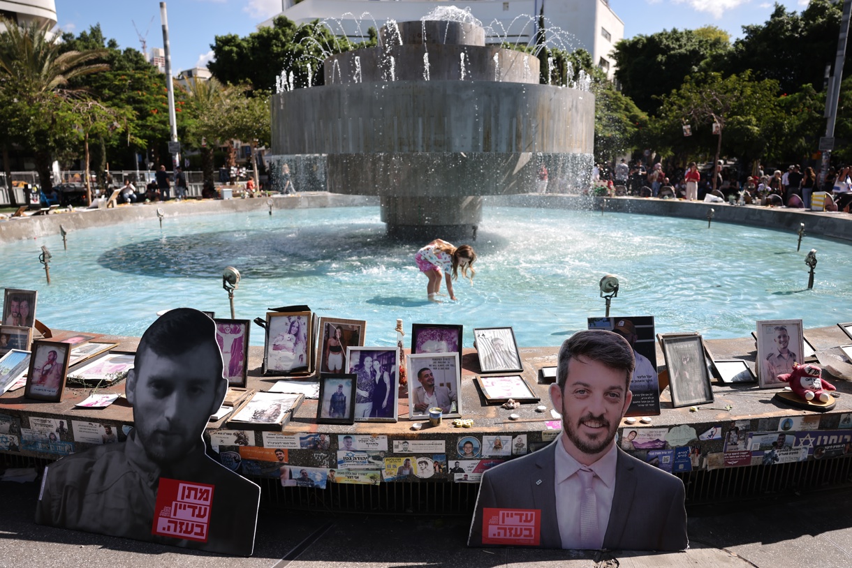 Personas colocando fotos de víctimas israelíes del ataque del 7 de octubre en la fuente de la plaza Dizengoff en Tel Aviv, Israel. (Foto de Abir Sultan de la agencia EFE)
