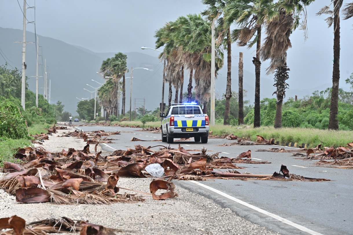 Un vehículo de la policía patrulla una carretera llena de escombros de árboles debido al paso del huracán Melissa, en Kingston (Jamaica). (Foto de Rudolph Brown de la agencia EFE)