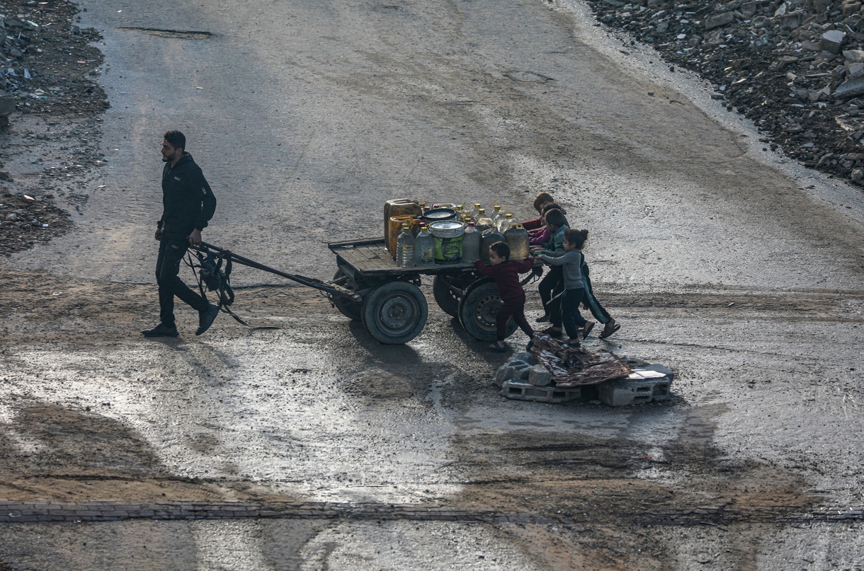 Niños palestinos que huyeron del norte de la Franja de Gaza caminan tras llenar el tanque de agua para sus familias en la Ciudad de Gaza, el 26 de noviembre de 2025. (Foto Mohammed Saber de la agencia EFE)