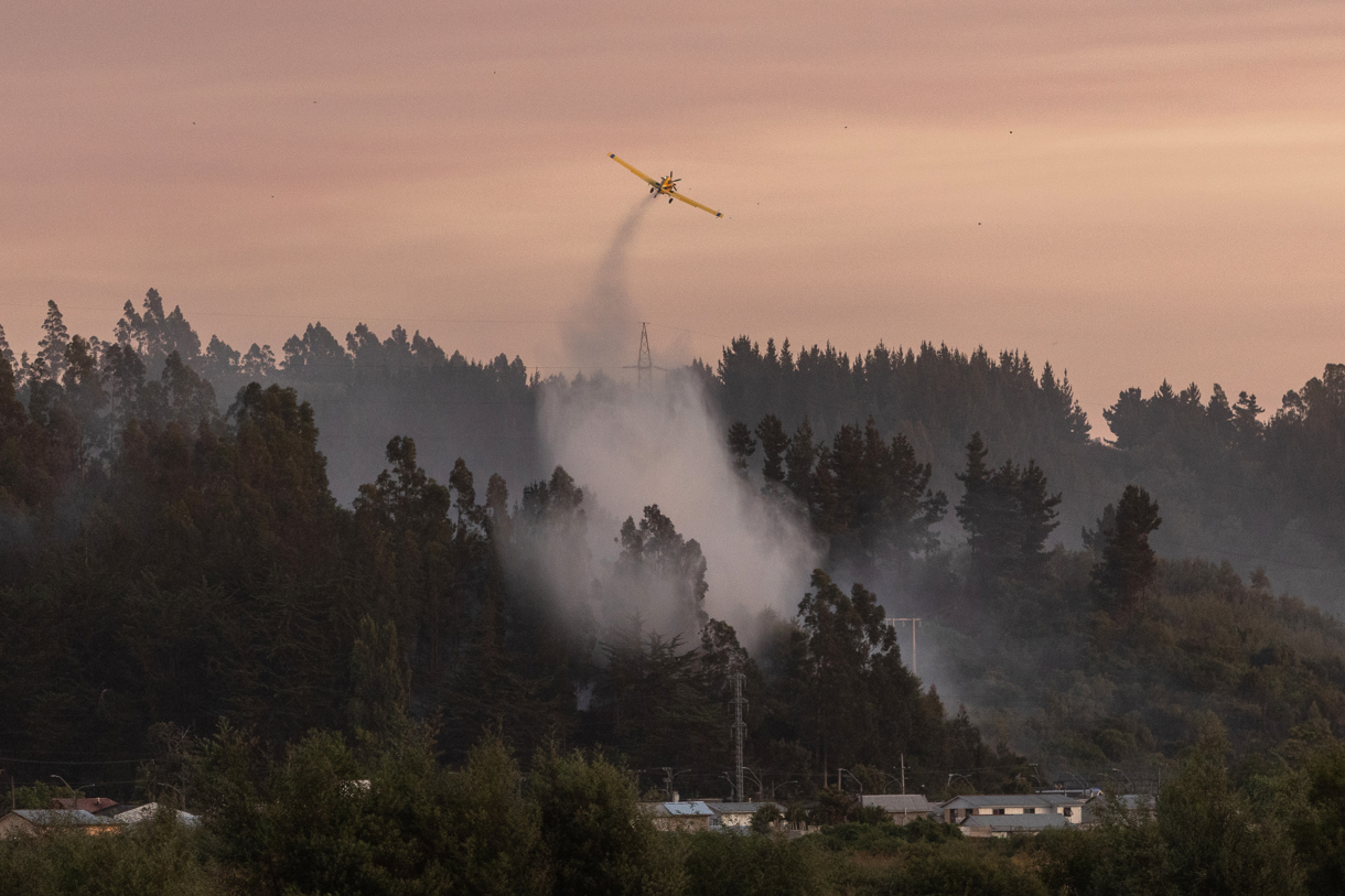 Un avión trabajando para controlar un incendio forestal este domingo, en la comuna de Penco, Concepción (Chile). (Foto de Pablo Hidalgo de la agencia EFE)