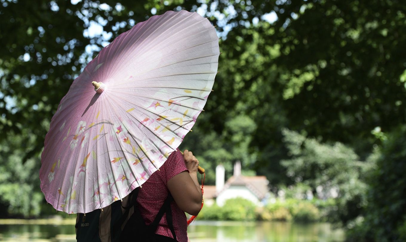 Una pareja se cubre del sol en el parque St. James en Londres, Reino Unido. (Foto de archivo de Andy Rain de la agencia EFE)