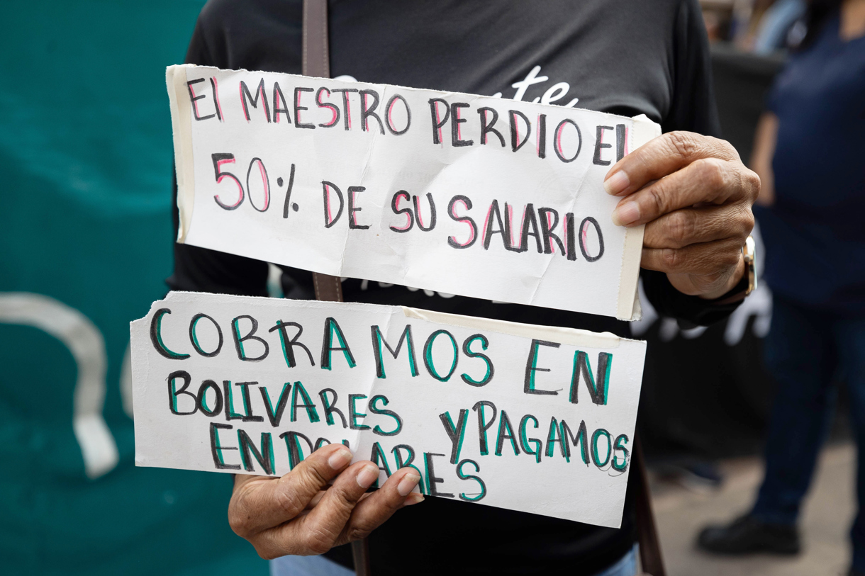 Una persona sostiene carteles durante una protesta para exigir un aumento de salarios y pensiones, congelados desde 2022 en 130 bolívares, unos 31 centavos de dólar al mes en la actualidad, este jueves frente al Ministerio del Trabajo en Caracas (Venezuela). (Foto de Ronald Peña R de la agencia EFE)