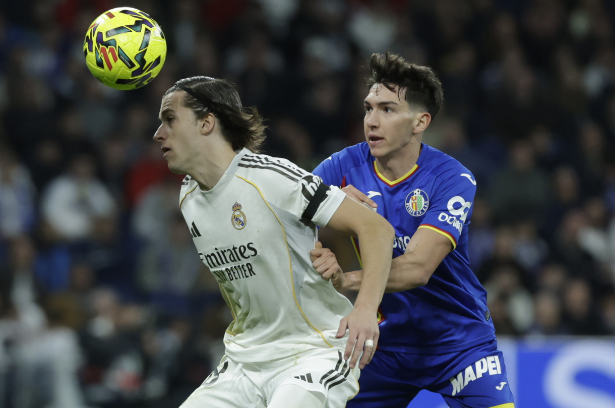El defensa del Real Madrid, Álvaro Carreras (i), en la que disputa el balón ante el delantero uruguayo del Getafe, Martín Satriano, durante el encuentro correspondiente a la jornada 26 de Laliga EA Sports que disputaron en el estadio Santiago Bernabéu. (Fotografía de archivo de Juanjo Martín de la agencia EFE)