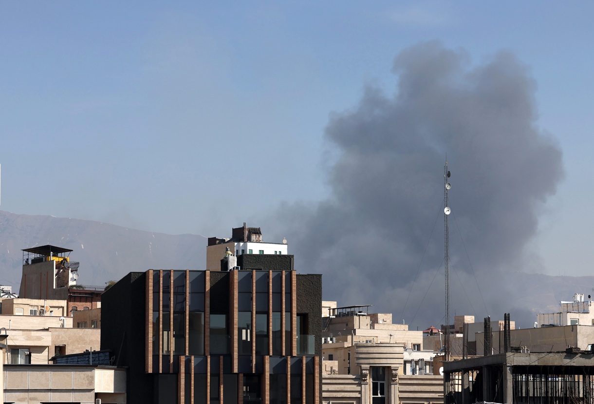 La gente corre en busca de refugio mientras el humo se eleva tras un ataque aéreo en el centro de Teherán, Irán, este jueves. (Foto de Abedin Taherkenareh de la agencia EFE)